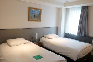 two beds in a hotel room with a window at Hotel Thomas Myeongdong in Seoul