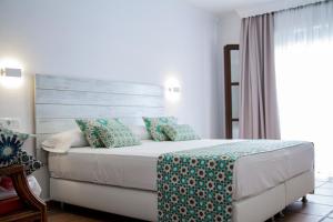 a bedroom with a bed with blue and white pillows at Hotel Avenida Playa in Zahara de los Atunes