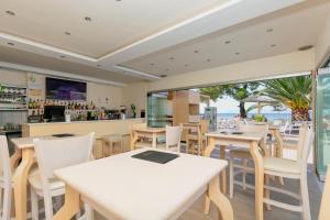 a restaurant with white tables and chairs and the beach at Mediterranean Beach Hotel in Skala Rachoniou