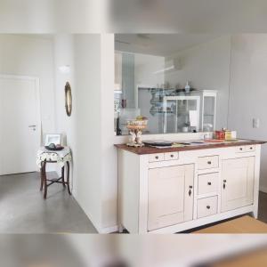 a kitchen with white cabinets and a table and a stool at Casa dos Edras in Miranda do Douro