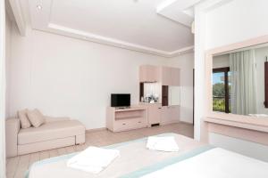 a white bedroom with a bed and a couch at Mediterranean Beach Hotel in Skala Rachoniou