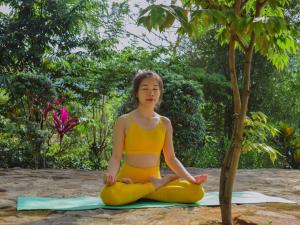 een vrouw in een yoga pose naast een boom bij Aqua Dunhinda Villa in Kandy