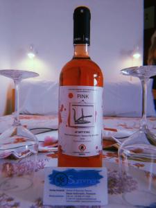 una botella de vino sentada en una mesa con dos copas en Summer Rooms en Skála Kallirákhis
