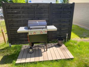 a grill sitting on a wooden deck next to a fence at Prestige Camping Brandenburg in Plaue