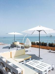 a patio with two white umbrellas and chairs and the ocean at Klaster SeaView Hotel in Chornomorsk