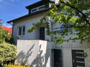 a white house with a black door and a tree at Apartamenty Parkowa in Koszalin