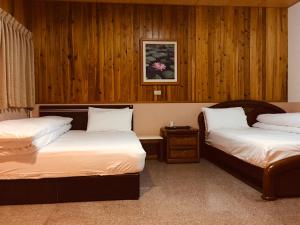 two beds in a room with wooden walls at Youlin Homestay in Meishan