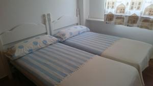 ein Bett mit zwei Kissen neben einem Fenster in der Unterkunft Ático Playa in Cartagena