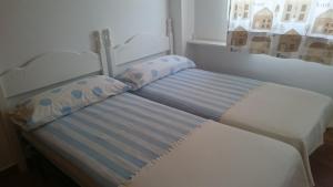 a bed with two pillows sitting next to a window at Ático Playa in Cartagena