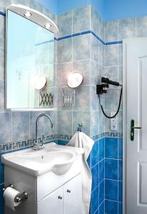 a blue tiled bathroom with a sink and a mirror at Villa Adam in Prague