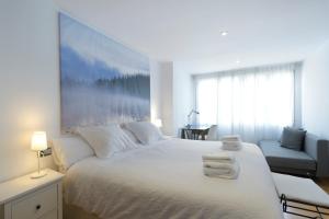 Un dormitorio con una cama blanca con toallas. en Andrews house, 60 m en el centro de Zaragoza, en Zaragoza