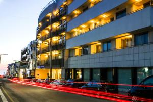 a city street with cars parked in front of a building at Hotel Praia in Nazaré