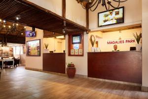 a restaurant with a bar in the middle of a room at First Group Magalies Park in Hartbeespoort