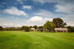 a large green field with a house in the background at First Group Magalies Park in Hartbeespoort