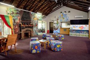 a room with tables and chairs and a fireplace at First Group Magalies Park in Hartbeespoort