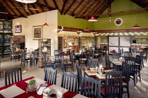 a dining room with tables and chairs in a restaurant at First Group Magalies Park in Hartbeespoort