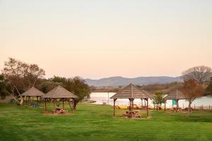 a group of picnic tables and umbrellas on a field at First Group Magalies Park in Hartbeespoort