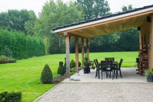 um pavilhão de madeira com uma mesa e cadeiras por baixo em Vakantiewoning Casa Maran in een groene omgeving te Heusden-Zolder em Heusden - Zolder