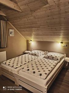 two twin beds in a room with a wooden ceiling at Sklípek u Svobodů in Velké Bílovice