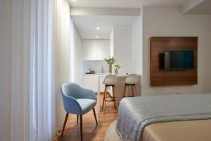 ein Schlafzimmer mit einem Bett und einem blauen Stuhl sowie eine Küche in der Unterkunft Signature Apartments Santa Catarina in Porto