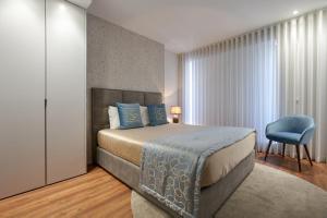 um quarto com uma cama e uma cadeira azul em Signature Apartments Santa Catarina em Porto