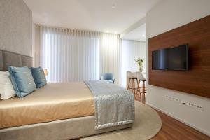 a hotel room with a bed and a flat screen tv at Signature Apartments Santa Catarina in Porto