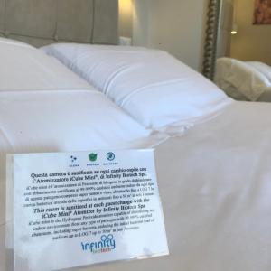 a white bed with white sheets and pillows at Hotel Villa Tiziana in Marina di Massa