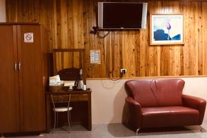 a room with a chair and a desk and a television at Youlin Homestay in Meishan