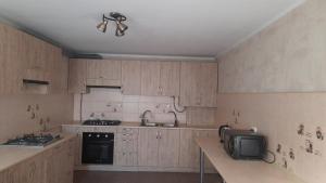 eine Küche mit Holzschränken und einer Mikrowelle in der Unterkunft Guest house Viola in Berdjansk