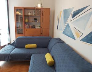 een woonkamer met een blauwe bank en gele kussens bij Bnbook - La casa sul Lago Maggiore in Ispra