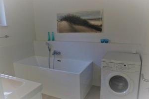 ein weißes Badezimmer mit einer Waschmaschine und einem Waschbecken in der Unterkunft Ferienwohnung Ströbele in Müllheim