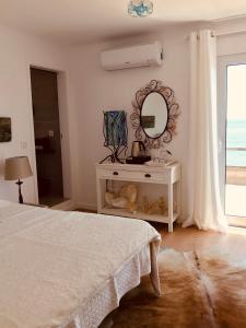 a white bedroom with a bed and a mirror at A Villa by the Sea Bed & Breakfast in Vila Franca do Campo