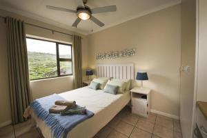 - une chambre avec un lit, un ventilateur de plafond et une fenêtre dans l'établissement Shearwater on Sea, Myoli, Sedgefield, à Sedgefield