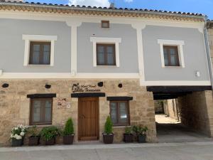 a white building with a brown door and windows at Villa Fontanas in Hontanas