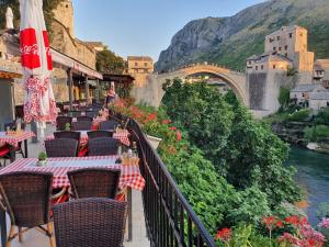 ein Balkon mit Tischen und Stühlen neben einer Brücke in der Unterkunft Hotel Bristol in Mostar