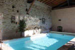 a large swimming pool in a room with a stone wall at L'Albane Chambres d'hôtes in Lauraguel