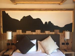 a bedroom with a bed with a mountain mural above it at Hotel alle Rose Family inspired garden and SPA in Cavedago