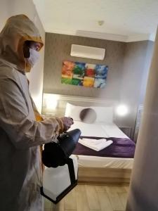 uma pessoa sentada numa cadeira num quarto com uma cama em Olimpiyat Hotel Izmir em Izmir