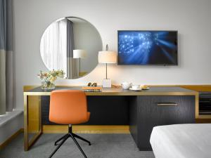a bedroom with a desk with a television on a wall at K+K Hotel Fenix in Prague
