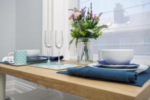 a table with plates and glasses and a vase of flowers at Stopover at SEABIRD APARTMENTS central Southsea in Portsmouth