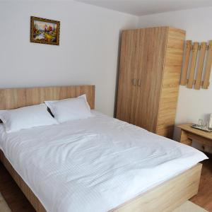 um quarto com uma cama branca e um armário de madeira em Casa Pedro em Blăjani