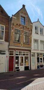a brick building with a red door on a street at In Den Visser in Dordrecht