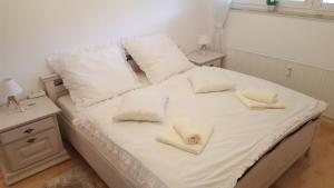 ein weißes Bett mit weißen Kissen und zwei Handtüchern darauf in der Unterkunft Ferienwohnung Herzblatt in Willingen