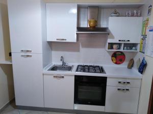 una cucina bianca con lavandino e piano cottura di La dimora delle 4 stagioni a Barletta