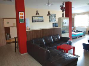 sala de estar con sofá negro y pared roja en BAILANDO Studio, en Neratovice