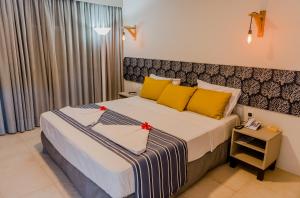 a bedroom with a large bed with yellow pillows at Baía Branca Beach Resort in Tamandaré
