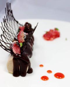 a chocolate dessert with berries on a white plate at Hotel Vela in Milano Marittima