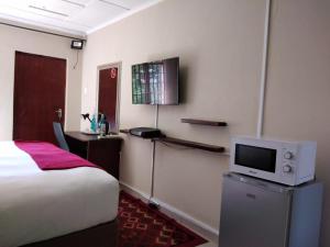 a hotel room with a bed and a tv at Angel Guest House in Lydenburg