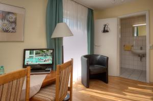 ein Wohnzimmer mit einem TV und einem Stuhl in der Unterkunft Hotel Brigitte in Bad Krozingen