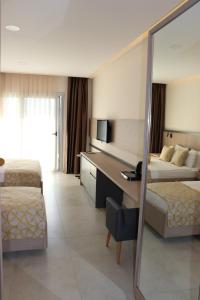 a hotel room with two beds and a desk at Zest Exclusive Hotel & Spa in Ortakent